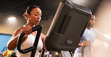 A woman intensely working out on an elliptical machine