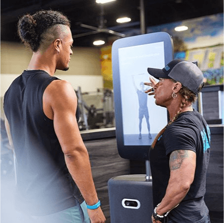 personal trainer explaining to excited eos gym member how the smart hub works
