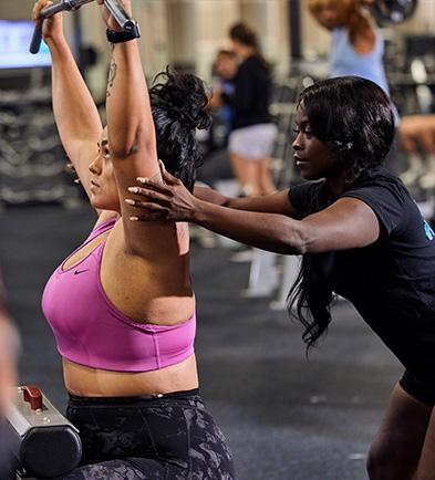 personal trainer helping eos member on lat pulldown cable machine
