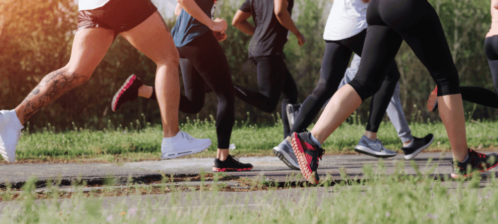 a group of athletic people running outside in the park