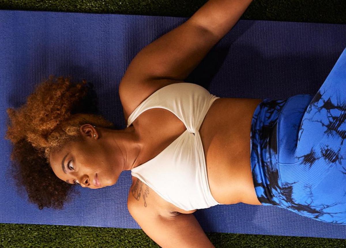eos gym member doing stretches on yoga mat