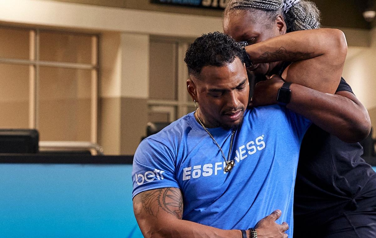 eos gym member getting stretched out by personal trainer