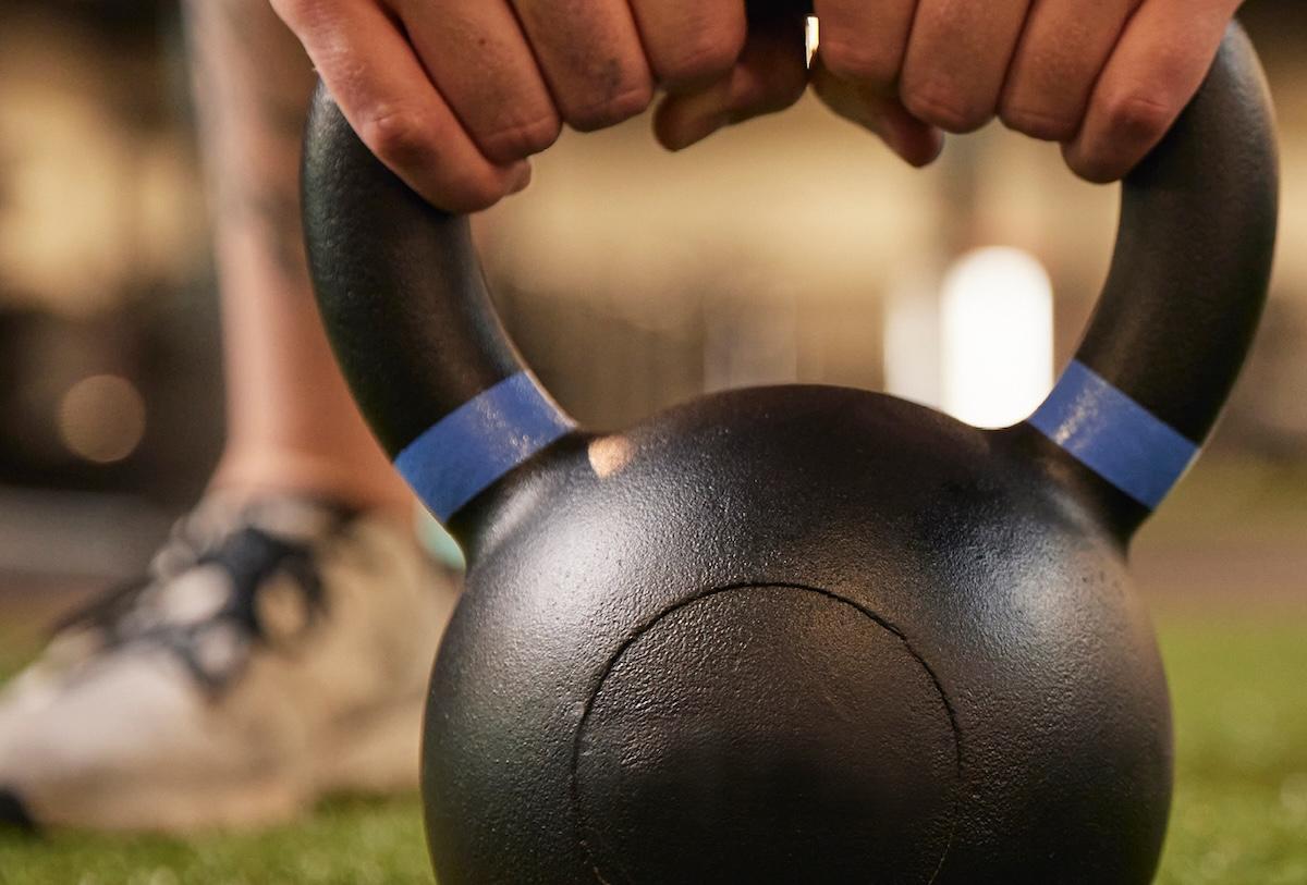 eos gym member doing kettlebell swings on turf