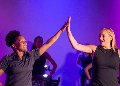 two eos gym members stretching in indoor turf while high fiving