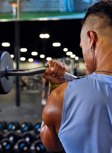 eos gym member curling a barbell looking at a large mirror