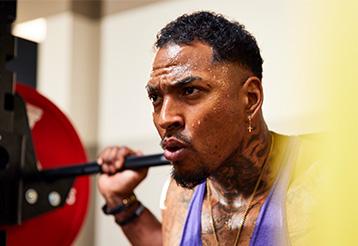 A man doing a squat with intense focus and determination in the gym.