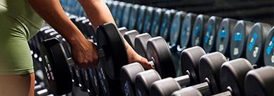 eos member unracking a dumbbell from a long rack of weights