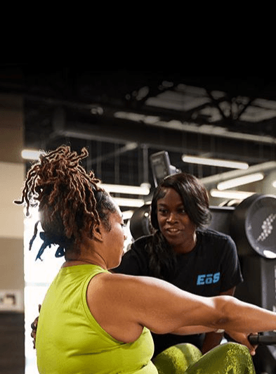 Gym trainer assisting a client on a rowing machine