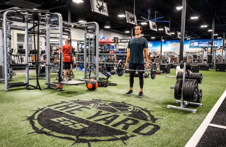 wide shot inside an eos branded gym where multiple members are doing a verity of strength and cardio exercises
