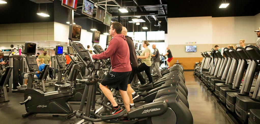 People using ellipticals and treadmills in gym