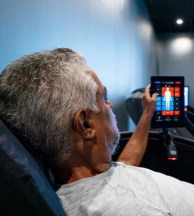 eos gym member adjusting the settings of a cryo chair in the middle of a dark room