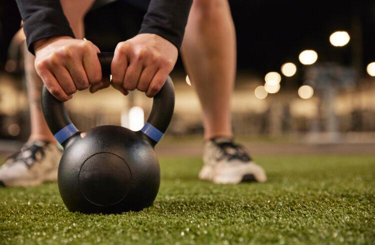 eos gym member lifting a kettle bell on eos branded indoor turf