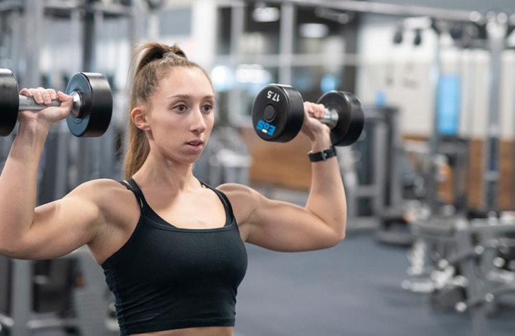 athletic eos fitness gym member shoulder pressing free weights