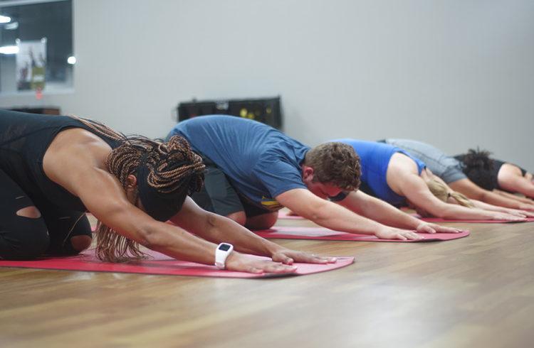 group of eos gym members in Child's Pose on yoga maps