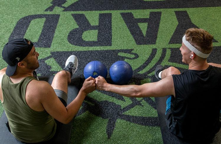 two eos gym members smiling and fit bumping after a workout