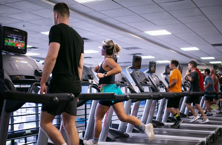 a group of eos gym member running on a row of modern treadmills