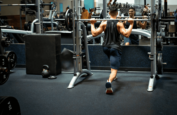 athletic eos gym member performing barbell lunches on smith machine