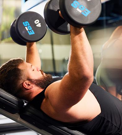 eos member lifting two dumbbells on an incline bench