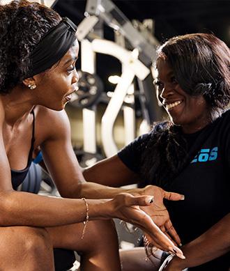 a smiling personal trainer giving fitness advice to an eos gym member
