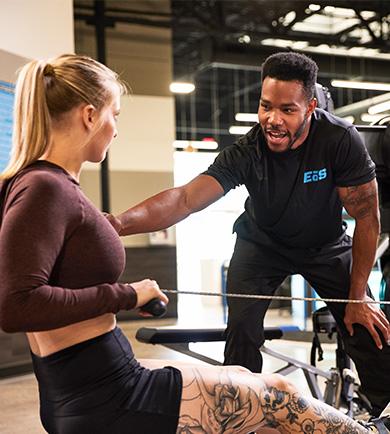 personal trainer instructing eos gym member on how to do a cable row