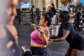 personal trainer helping eos gym member with cable pulldown
