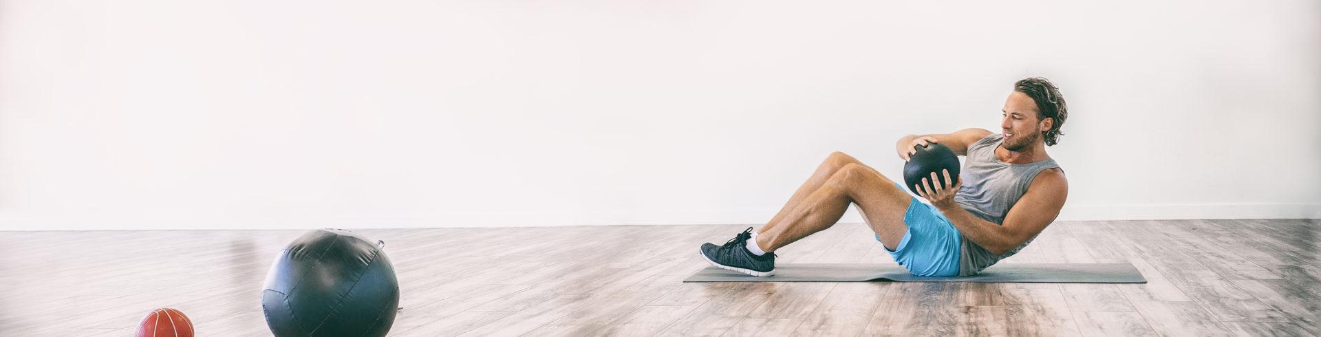Man doing a seated russian twist with a medicine ball