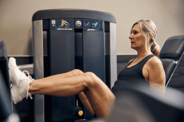 woman using senior workout equipment at the gym for lower body