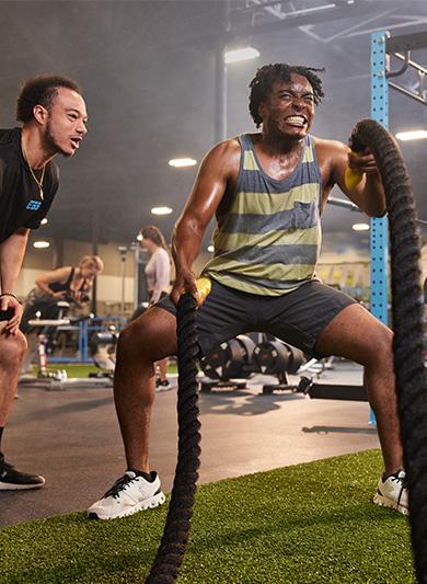 personal trainer showing eos gym member how to use the battle ropes