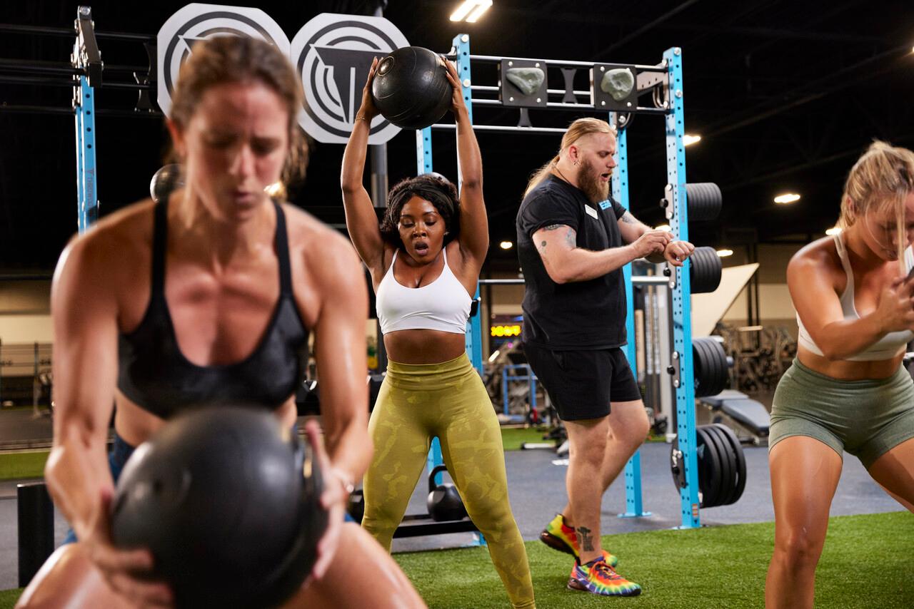 a group of athletic eos gym members doing a hard workout inside a modern gym