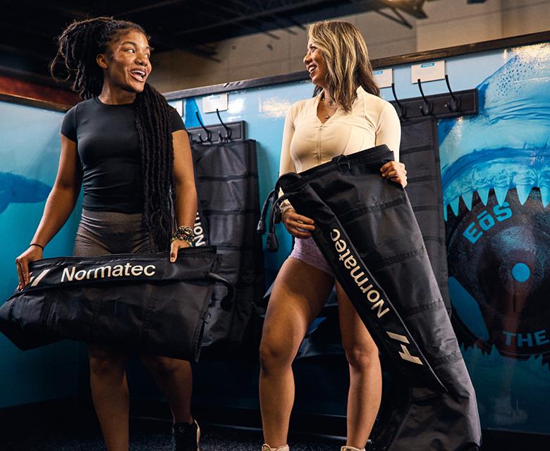 two eos gym members getting ready to use a compression boot