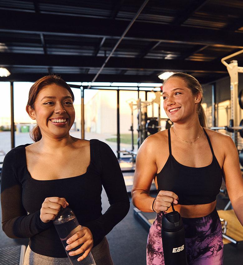 two fit eos gym members smiling at one another