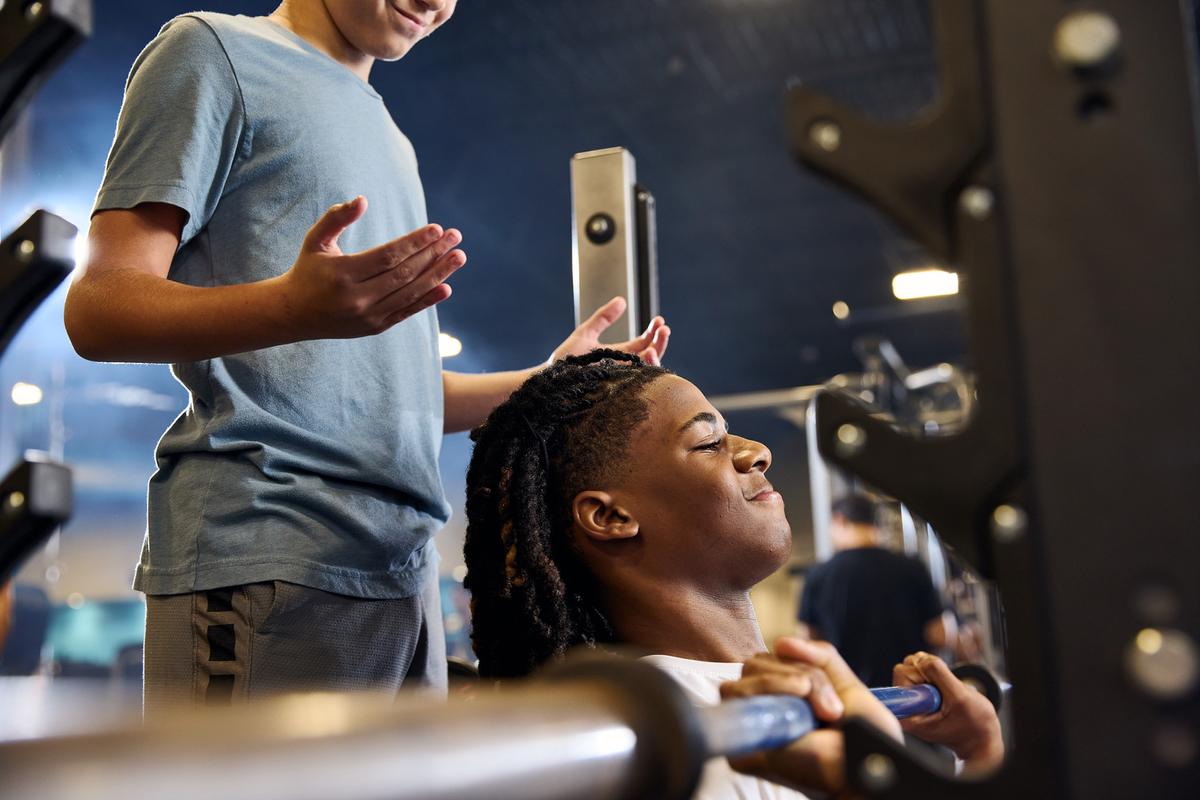 eos youth spotting another on the bench press