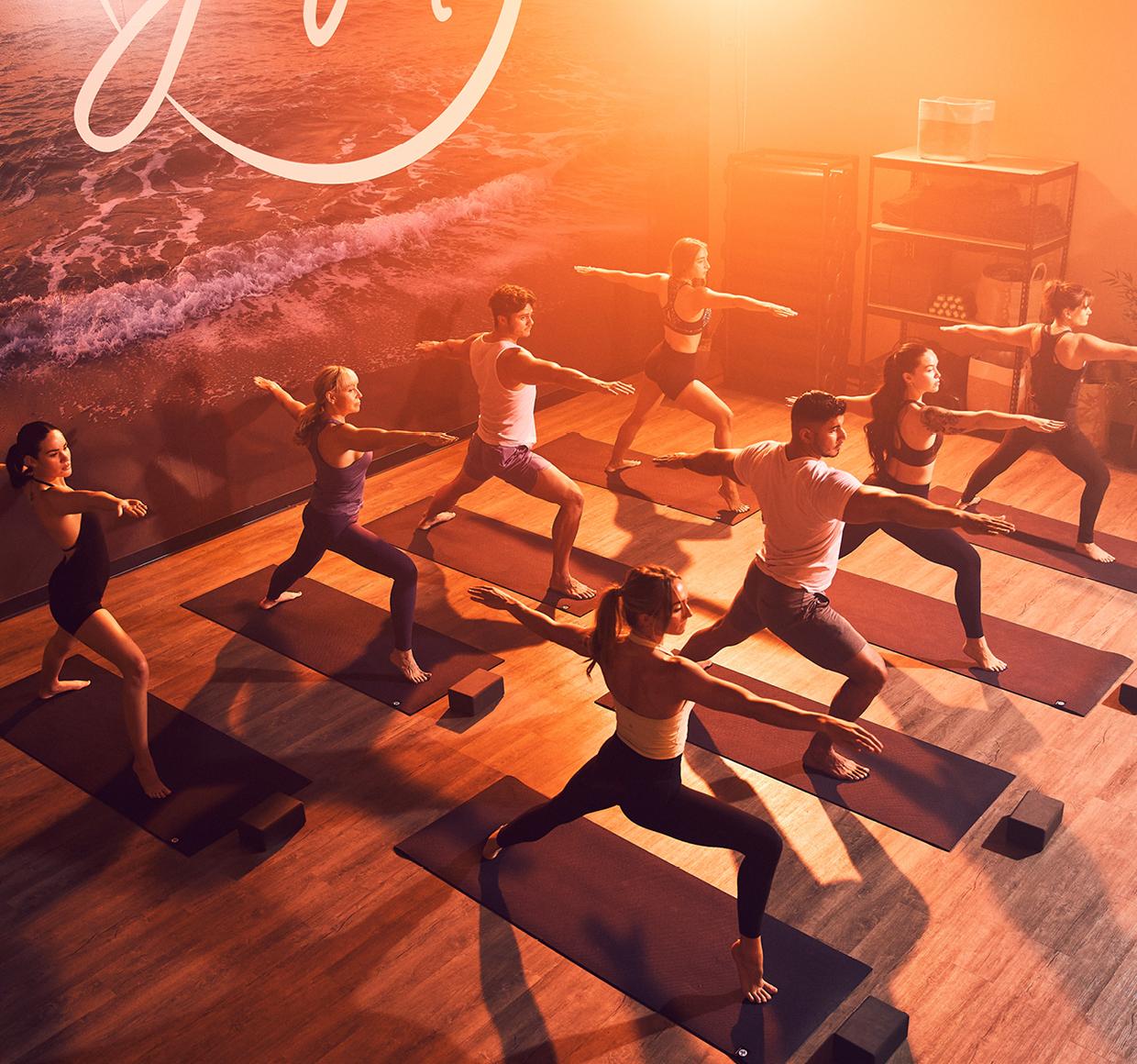 a group of eos gym members all performing a praise the sun worrier pose