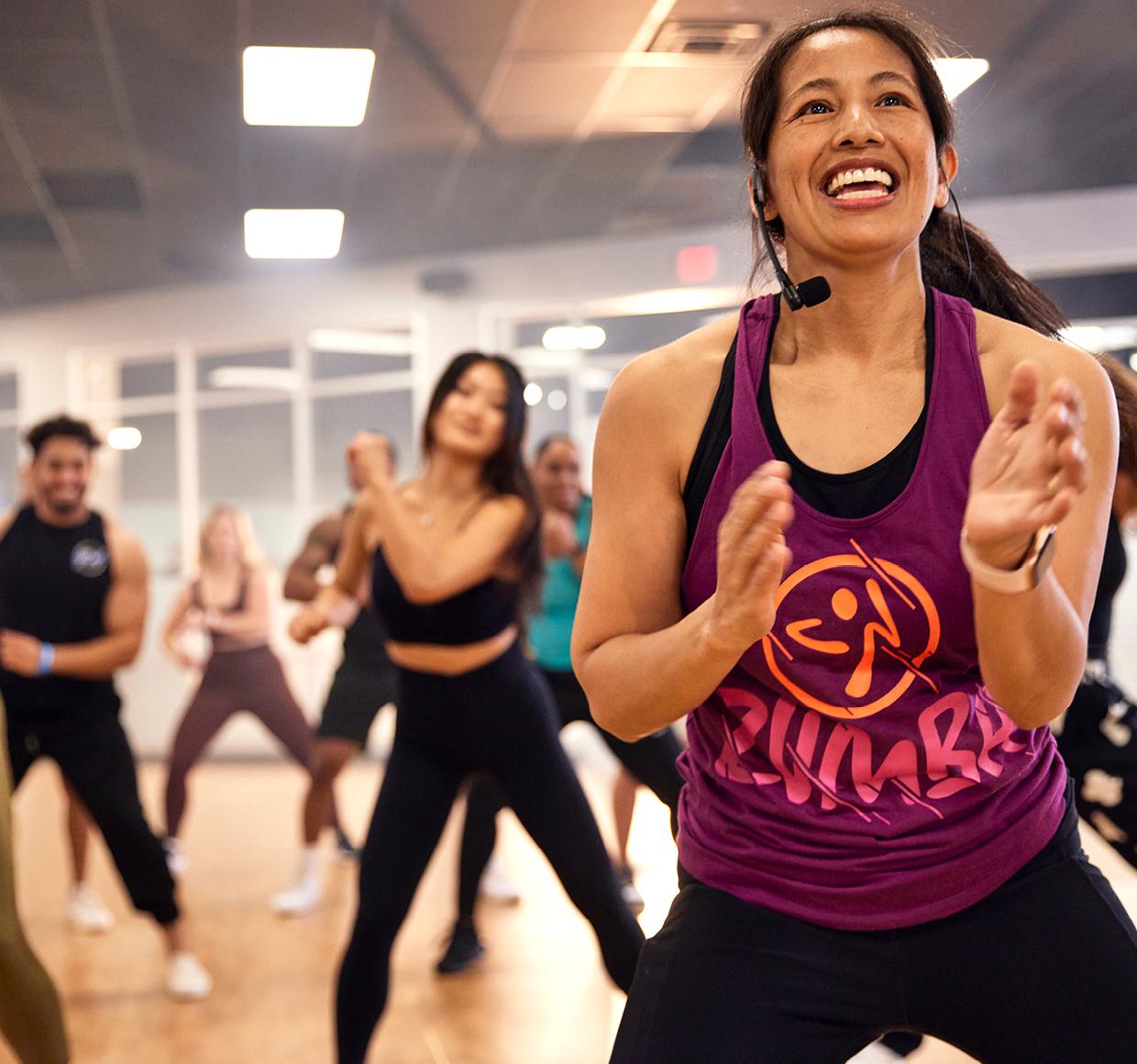 a group of smiling eos gym members in the middle of a zumba dance workout
