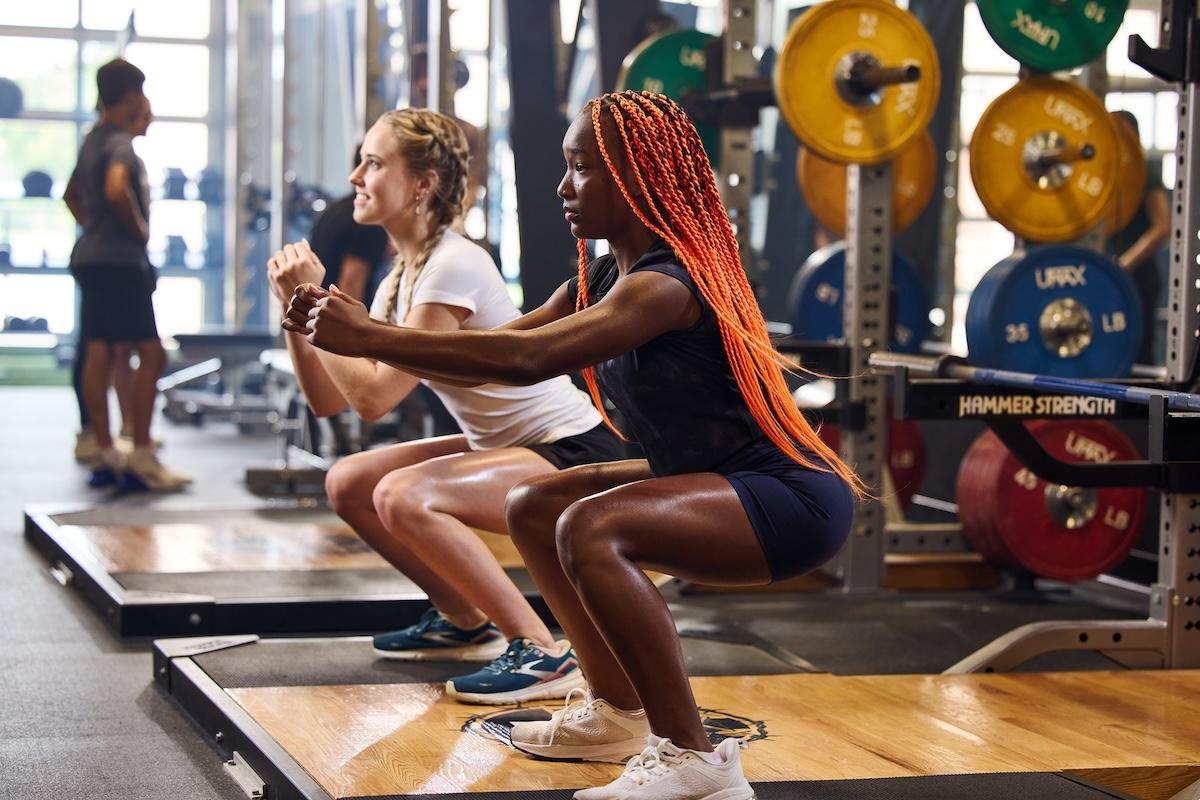 two eos teen gym member squatting