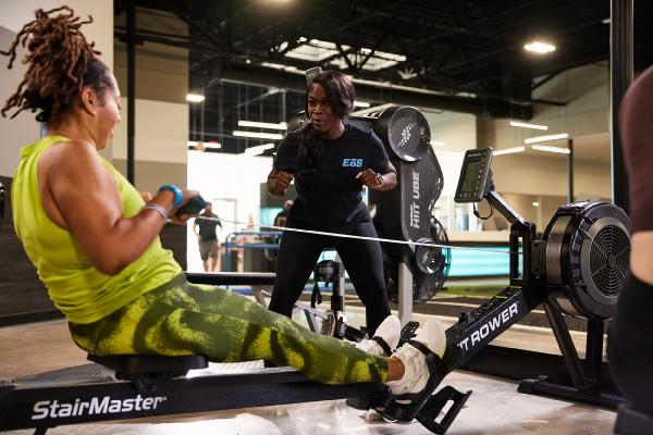 eos gym member getting help from pt on rowing machine