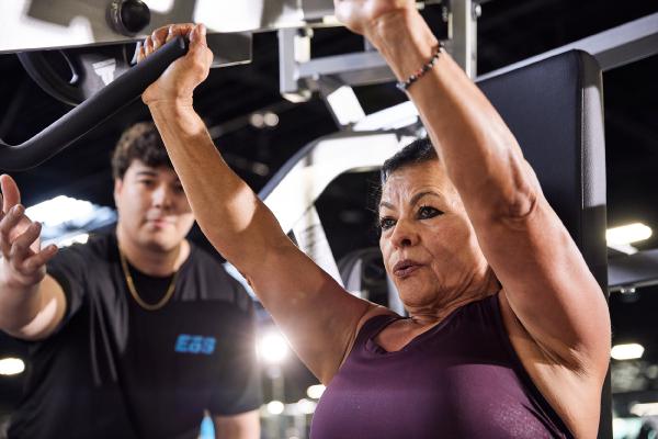 eos gym member getting help from pt on chest press