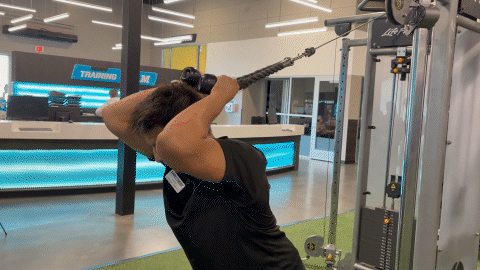 eos fitness member doing overhead tricep extensions on cable machine