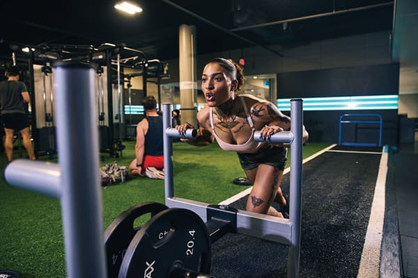 eos fitness member performing a sled push on the eos yard