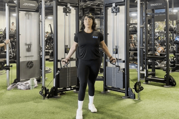 EōS Fitness member performing cable curls in the gym.