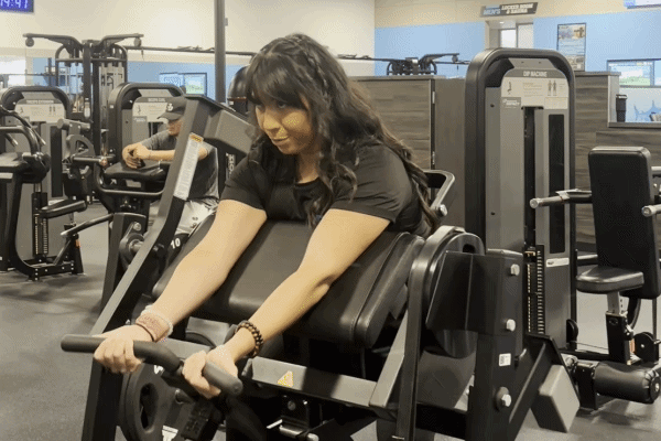 EōS Fitness member performing preacher curls in the gym.