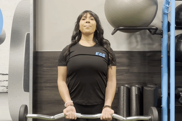 EōS Fitness member performing EZ-bar curls in the gym.