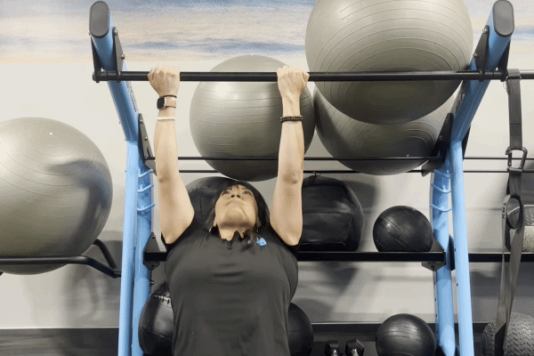 EōS Fitness member performing chin-ups in the gym.