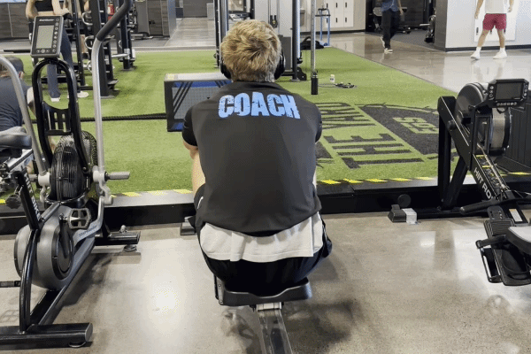 EōS Fitness member performing EZ-bar curls in the gym.