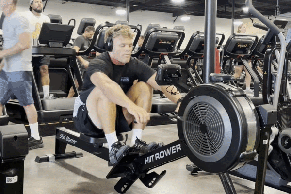 EōS Fitness member performing EZ-bar curls in the gym.