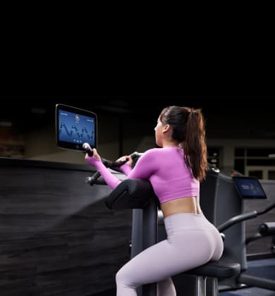 over the shoulder view of the smart equipment screen and an eos gym member performing a shoulder press on it